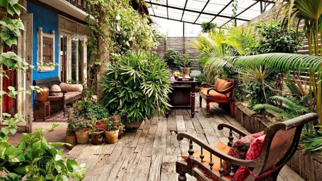 Lush landscaped garden at Sabyasachi Mukherjee Kolkata home with dense greenery, flowering plants, and large windows blending indoor and outdoor spaces.